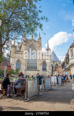 Gäste vor dem Vanilla Cafe sitzen an ihren Tischen im York Minster im Hintergrund, York, Yorkshire, England. Stockfoto