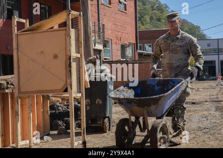 Marshall, Usa. Oktober 2024. Austin Ingie, dem 502. Infanterieregiment zugeteilt, schiebt eine Schubkarre während der Säuberung nach dem Hurrikan Helene, 10. Oktober 2024 in Marshall, North Carolina. Quelle: PFC. Cristian Lopez/US Army Photo/Alamy Live News Stockfoto