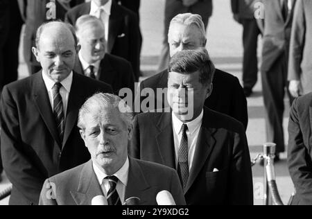 Der britische Premierminister Harold Macmillan hält während der Ankunftszeremonien zu seinen Ehren, von links nach rechts hinter MacMillan: Dean Rusk, US-Außenminister; Sir Norman Brook, Minister des Kabinetts des Premierministers; US-Präsident John F. Kennedy; David K. E. Bruce, US-Botschafter in Großbritannien; Andrews Air Force Base, Prince George's County, Maryland, USA, Cecil Stoughton, Fotos Des Weißen Hauses, 27. April 1962 Stockfoto