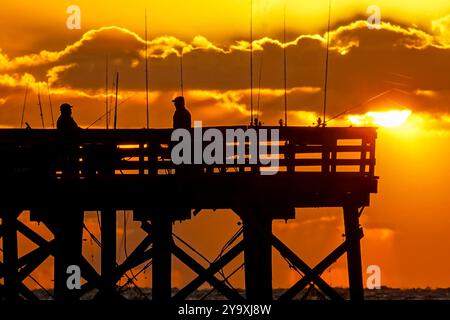 Isle Of Palms, Usa. Oktober 2024. Fischer, die von einem dramatischen Sonnenaufgang umgeben sind, werfen ihre Linien am Ende des Isle of Palms Pier am 11. Oktober 2024 in Isle of Palms, South Carolina. Hurrikan Milton zog 400 Meilen weiter nach Süden, führte aber herbstliches Wetter entlang der Küste, während die Stürme aufwachen. Quelle: Richard Ellis/Richard Ellis/Alamy Live News Stockfoto