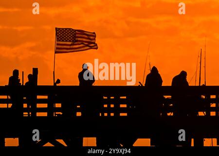 Isle Of Palms, Usa. Oktober 2024. Fisherman Silhouetten von einem dramatischen Sonnenaufgang werfen ihre Linien vor der Isle of Palms Pier am 11. Oktober 2024 in Isle of Palms, South Carolina. Hurrikan Milton zog 400 Meilen weiter nach Süden, führte aber herbstliches Wetter entlang der Küste, während die Stürme aufwachen. Quelle: Richard Ellis/Richard Ellis/Alamy Live News Stockfoto