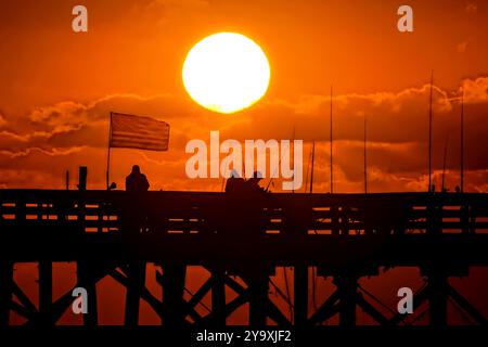 Isle Of Palms, Usa. Oktober 2024. Fisherman Silhouetten von einem dramatischen Sonnenaufgang werfen ihre Linien vor der Isle of Palms Pier am 11. Oktober 2024 in Isle of Palms, South Carolina. Hurrikan Milton zog 400 Meilen weiter nach Süden, führte aber herbstliches Wetter entlang der Küste, während die Stürme aufwachen. Quelle: Richard Ellis/Richard Ellis/Alamy Live News Stockfoto