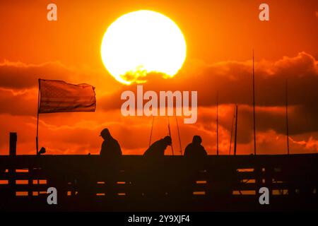 Isle Of Palms, Usa. Oktober 2024. Fisherman Silhouetten von einem dramatischen Sonnenaufgang werfen ihre Linien vor der Isle of Palms Pier am 11. Oktober 2024 in Isle of Palms, South Carolina. Hurrikan Milton zog 400 Meilen weiter nach Süden, führte aber herbstliches Wetter entlang der Küste, während die Stürme aufwachen. Quelle: Richard Ellis/Richard Ellis/Alamy Live News Stockfoto