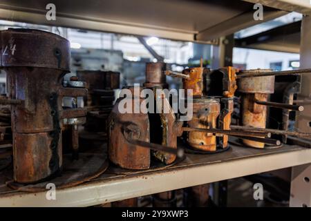 Nahaufnahme alter, verrosteter Metallformen auf einem Regal in einer industriellen Werkstatt, die Anzeichen von Verschleiß und Verfall zeigen, was einen Sinn für Geschichte und Geschichte weckt Stockfoto
