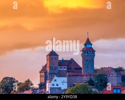 Kaiserburg Nürnberg im Sonnenuntergang, 11.10.2024 die Nürnberger Kaiserburg im warmen Licht eines herbstlichen Sonnenuntergangs. Die mittelalterlichen Türme und Mauern der Burg heben sich eindrucksvoll gegen den orangefarbenen Himmel ab, der von den letzten Strahlen der untergehenden Sonne beleuchtet wird. Die herbstlichen Bäume am Fuß der Burg ergänzen die malerische Szenerie. Nürnberg Wöhrd Bayern Deutschland *** Nürnberg Reichsschloss bei Sonnenuntergang, 11 10 2024 die Nürnberger Reichsburg im warmen Licht eines herbstlichen Sonnenuntergangs stechen die mittelalterlichen Türme und Mauern der Burg hervor Stockfoto