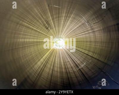 Foto von der Innenseite eines großen Abschnitts aus schwarzem HDPE-Rohr aus hochdichtem Polyethylen mit Sonnenschein vom anderen Ende Stockfoto