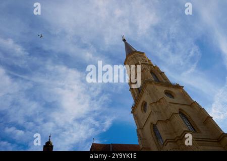 Cluj-Napoca, Rumänien. 20. September 2024: Der Flug der LOT Polish Airlines von Cluj nach Warschau fliegt über der römisch-katholischen Kirche St. Michael, Stockfoto