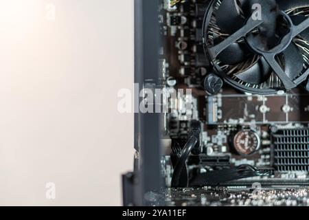 Nahaufnahme einer Computerplatine und eines Lüfters in einem PC-Gehäuse mit komplexen elektronischen Komponenten und Verkabelung. Stockfoto