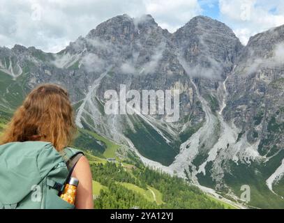 Ein junges Mädchen steht im Vordergrund und blickt staunend auf den atemberaubenden Blick auf die österreichischen Alpen Stockfoto