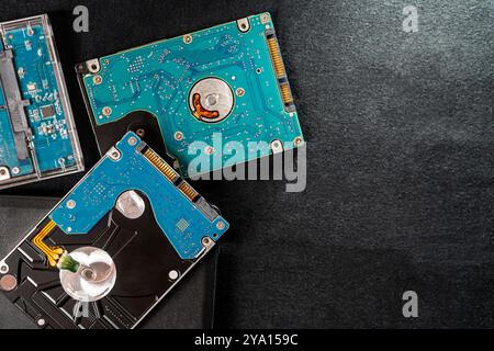 Nahaufnahme mehrerer Festplattenlaufwerke (HDDs) auf einer dunklen Oberfläche. Das Bild zeigt die komplizierten Leiterplatten und mechanischen Komponenten des Stockfoto