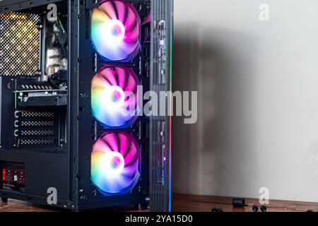 Nahaufnahme eines modernen Computergehäuses mit drei RGB-Lüftern. Die Fans zeigen ein lebhaftes Farbspektrum, das eine optisch ansprechende Optik schafft Stockfoto