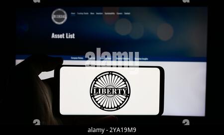 In dieser Abbildung hält eine Person ein Handy mit dem Logo des US-amerikanischen Medienunternehmens Liberty Media Corporation vor der Unternehmenswebsite. Stockfoto
