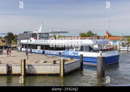 Ein großes Passagierschiff mit Flagge liegt am Bootssteg im sonnigen Hafen Rügen, Hiddensee Stockfoto