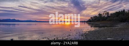 Ruhiges Panorama eines Sees bei Sonnenuntergang mit sanften Farben und Wolkenformationen, Chiemsee Stockfoto