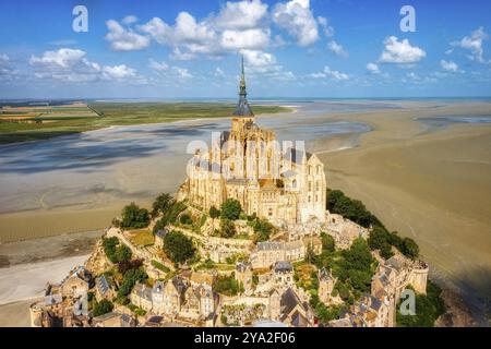 Historische Abtei auf einer felsigen Insel, umgeben von Sandstränden und blauem Himmel, Le Mont-Saint-Michel Stockfoto