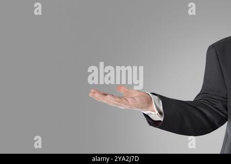 Geschäftsmann mit offener Hand vor grauem Hintergrund Stockfoto