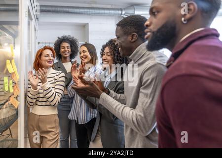 Verschiedene Kollegen applaudieren am Ende des kreativen Brainstormings in einem Coworking Space Stockfoto