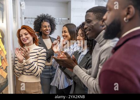 Vielfältige Teamarbeit, die am Ende eines Brainstorming-Meetings in einem Coworking-Raum applaudiert Stockfoto