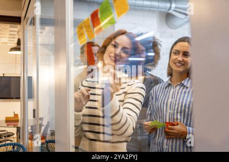 Blick aus einem Glas verschiedener weiblicher Kollegen, die an einem Brainstorming-Prozess in einem Coworking teilnehmen Stockfoto
