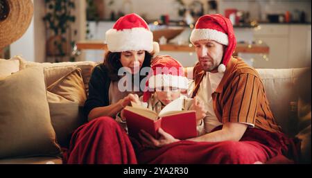 Weihnachten, Familie und Buch zu Hause zum Lesen, Lernen und traditionelle Literatur für die religiöse Erziehung. Eltern, Kind und Bibel auf Sofa Stockfoto