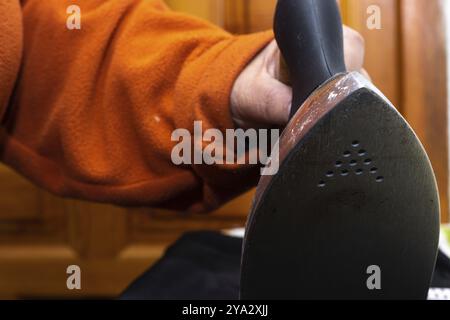 Nahaufnahme der Hände der Frau, die bügelt. Hände einer Seniorin, die ein Handtuch bügelt Stockfoto