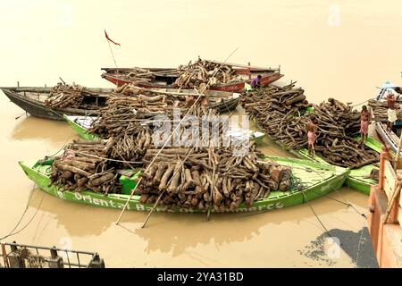 Mit Brennholz beladene Boote für Einäscherungszeremonien auf dem Fluss Ganges, Marnikarnika Ghat, Varanasi, Uttar Pradesh, Indien. Stockfoto