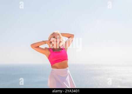 Eine Frau in rosa Oberteil und weißem Rock steht am Strand Stockfoto