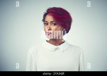 Afrikanische Frauen-, Gesichts- und Haarpflege im Atelier für Selbstvertrauen, Textur und Kosmetik mit roter Färbung. Weibliche Person, Porträt und Behandlung auf Grau Stockfoto