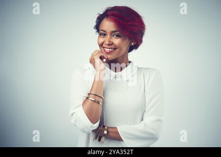 Afrikanische Frau, Porträt- und Haarpflege im Studio für Selbstvertrauen, Textur und Kosmetik mit roter Färbung. Weibliche Person, glücklich und ästhetisch auf Grau Stockfoto