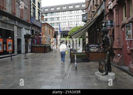 Ein regnerischer Tag im Stadtzentrum, an dem eine Frau an der Phil Lynott Statue vorbeikommt. Dublin, Irland, Europa Stockfoto