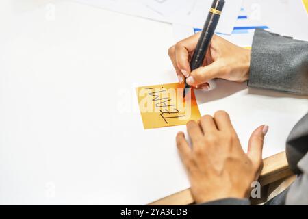 Nahaufnahme der Hände einer Geschäftsfrau, die beim Brainstorming-Meeting in einem modernen Coworking Teamwort in einer Notiz schreibt Stockfoto