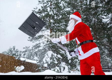 Der Weihnachtsmann reinigt im Winter draußen nach einem Schneefall Schnee mit Schaufel. Die Straßen im Dorf zu reinigen, die Passage für Autos freizumachen, schwierig Stockfoto