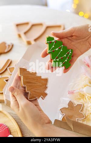 Eine Frau, die Weihnachtskuchen in Form von Tannenbäumen in der Hand hält. Stockfoto