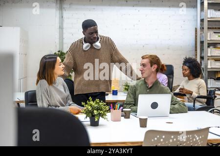 Multi-ethnische Kollegen sprechen abgelenkt und arbeiten in einem Coworking Stockfoto