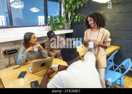 Glückliche Kollegen, die sich während der Kaffeepause in der Kantine eines Coworking unterhalten Stockfoto