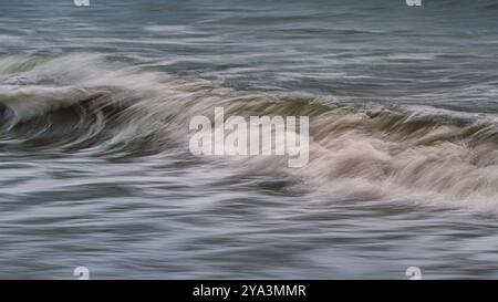 Ein abstraktes, langbelichtetes Bild einer Welle, die am Strand bricht Stockfoto