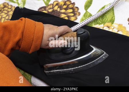 Nahaufnahme der Hände der Frau, die bügelt. Hände einer Seniorin, die ein Handtuch bügelt Stockfoto