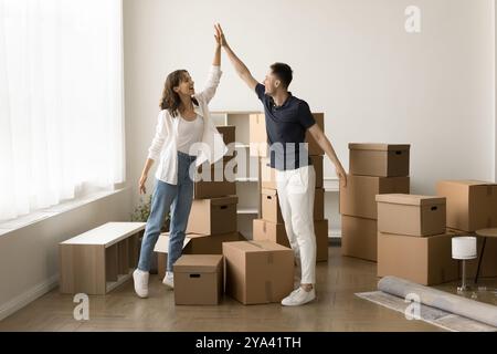 Junge Paare geben High 5 im Wohnzimmer mit Kisten Stockfoto