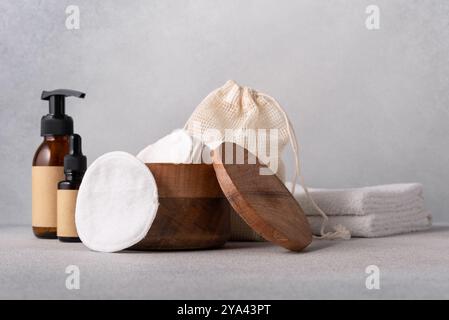 Natürliche Hautpflegeprodukte auf minimalistischer Oberfläche mit Holzbehältern, wiederverwendbaren Wattepads, umweltfreundlichen Verpackungen und Essentials für das Spa. Idee Stockfoto