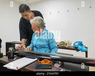 Shenyang, Chinas Provinz Liaoning. Oktober 2024. Ein Senior der Dalian Seniors University lernt Guqin zu spielen, ein gerupftes siebensaitiges traditionelles chinesisches Musikinstrument, unter der Leitung eines Lehrers in Dalian, nordöstlicher Provinz Liaoning, 9. Oktober 2024. ZU „China Focus: Silver-haired Seniors Take on University Life“ Credit: Zhang Boqun/Xinhua/Alamy Live News Stockfoto