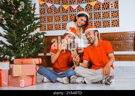 Eine fröhliche Weihnachtsfeier mit Freunden, die sich unter dem Weihnachtsbaum versammelt haben Stockfoto