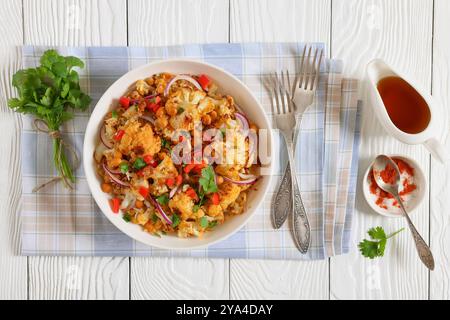 Gebratener Blumenkohl-Quinoa-Salat mit Walnüssen, rotem Pfeffer, Zwiebeln und Koriander, mit Olivenöl und Zitronensaft in einer weißen Schüssel auf weiß getränkt Stockfoto