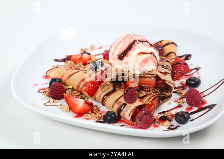 Frisches Eis in einem Crêpe, dekoriert mit gemischten Beeren und Schokoladensirup Stockfoto