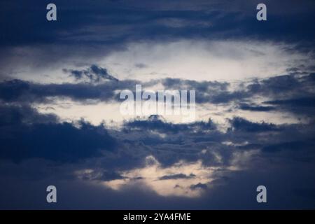 Ein dramatischer Himmel voller dunkler Wolken in der Abenddämmerung, der einen beeindruckenden Kontrast zwischen Licht und Schatten in einer friedlichen Atmosphäre einfängt. Stockfoto
