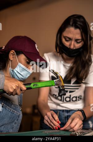 Zwei Frauen arbeiten mit Hummer an Ledergeldbörse. Doha, Katar, 07. Februar 2021 Stockfoto