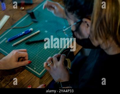 Frauen, die mit der Nadel an Ledergeldbörse arbeiten. Doha, Katar, 07. Februar 2021 Stockfoto