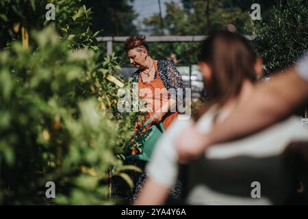 Ältere Frau, die mit Kindern in einem üppigen Garten gärtet Stockfoto