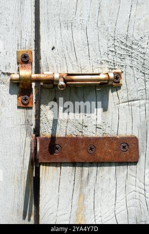 Ein rostiger Bolzen auf dem Hintergrund einer sonnenverbrannten HolzLeinwand Stockfoto