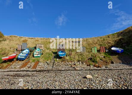 Fünf traditionelle Holzfischboote fuhren auf dem grasbewachsenen Ufer am alten Hafen von Portlethen Village an der Küste von Aberdeenshire. Stockfoto