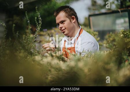 Junger Gärtner mit Down-Syndrom, der im Freien Pflanzen pflegt Stockfoto